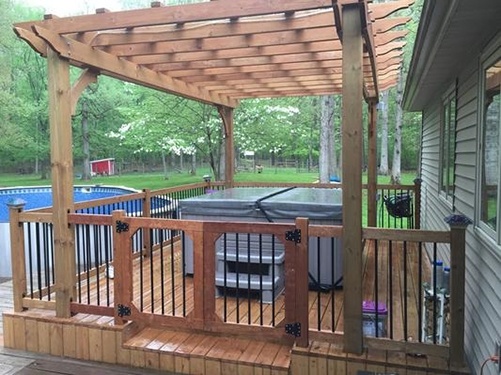 a Caldera hot tub sits in a backyard underneath a pergola with a safety fence